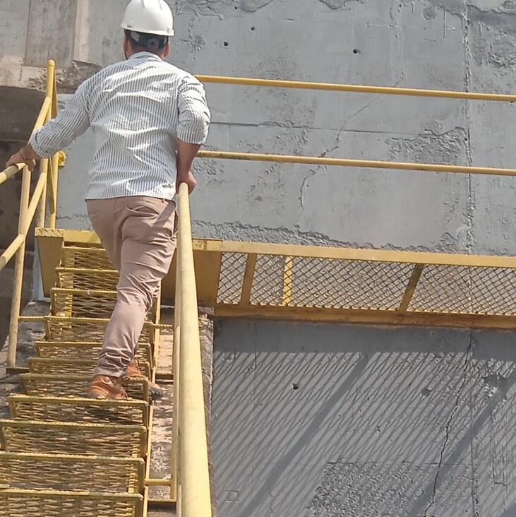 Engenheiro com capacete subindo escada de acesso para inspeção em estrutura de concreto